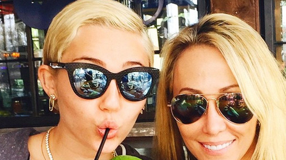 Miley tar en drink med sin mamma. 